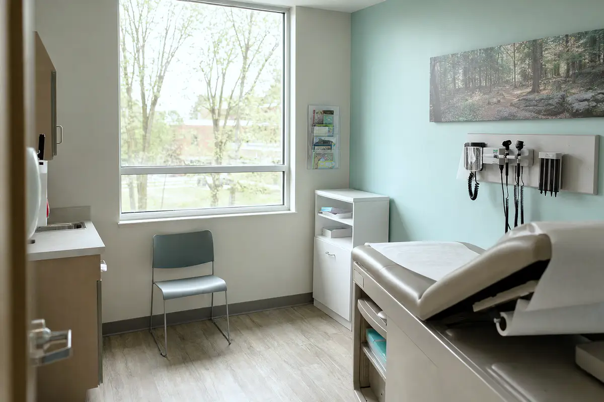 A quiet pediatric exam room with a window and a small chair.