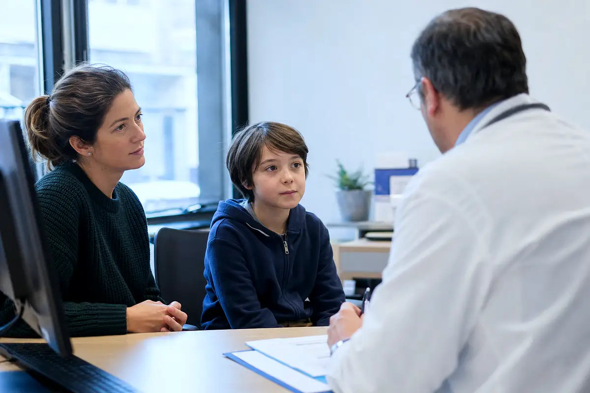 A parent and child talking with a physician in a bright office.